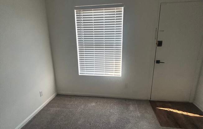 A room with a window and a concrete wall.