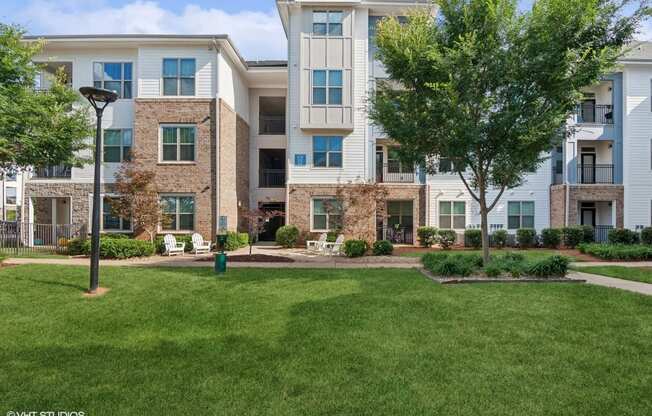 an exterior view of an apartment building with green grass and trees