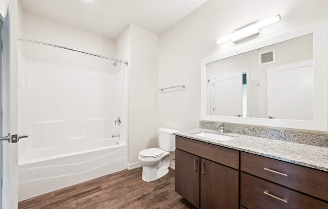 a bathroom with a shower toilet sink and mirror at Maven on Broadway Apartments, Rochester, Minnesota
