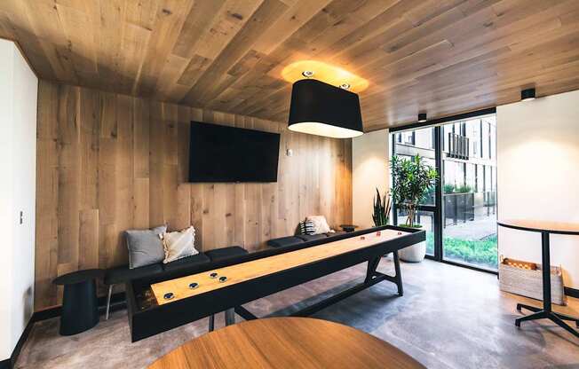 A room with a long black table and a television mounted on the wall.