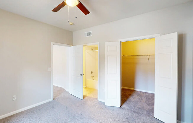 A room with a ceiling fan and carpeted floor.