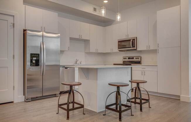A kitchen with white cabinets and a stainless steel refrigerator.