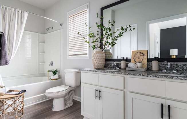 A white bathroom with a toilet, sink, and mirror.