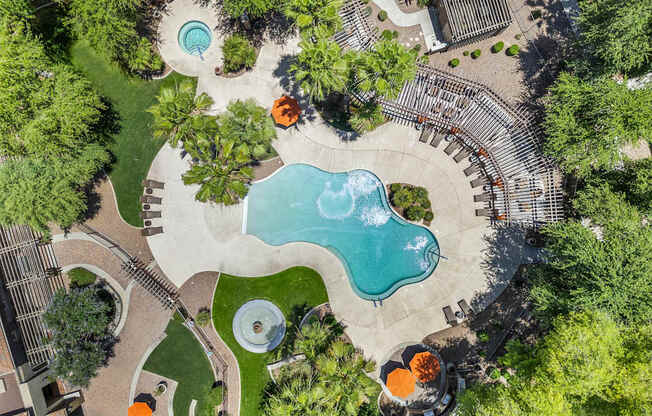 A large outdoor swimming pool surrounded by trees and grass.