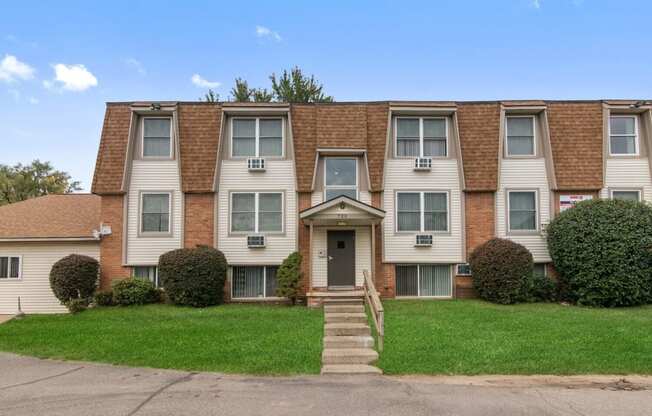 an apartment building with a lawn and a blue sky