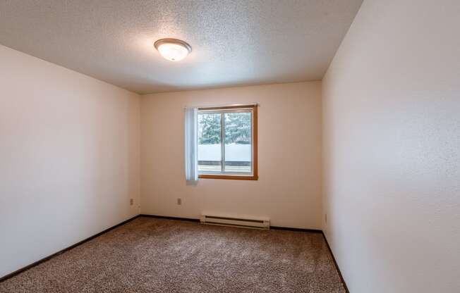 a bedroom with a window and carpeted floors. Fargo, ND Long Island Apartments.