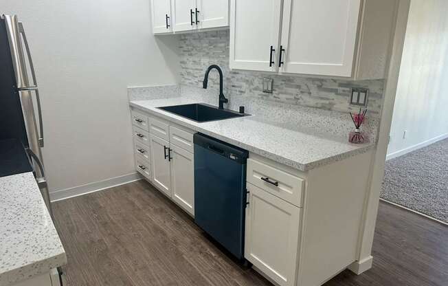 A kitchen with white cabinets and a blue dishwasher. at Camino de Oro Apartments, Torrance, CA, 90505