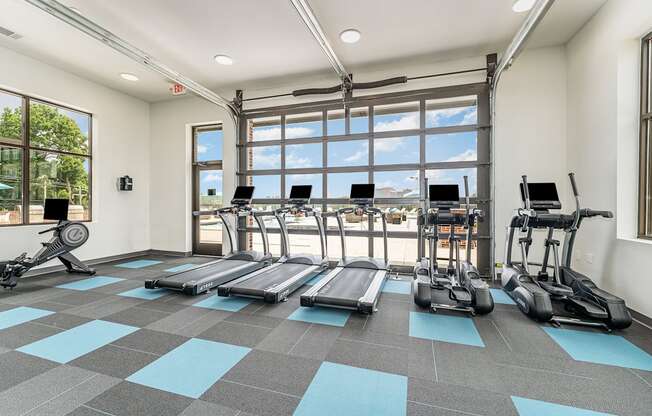 a workout room with treadmills and elliptical trainers