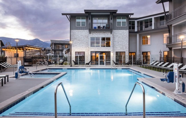 a swimming pool in front of an apartment building at dusk