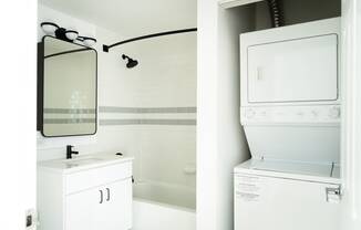 a white washer and dryer and a mirror in a bathroom