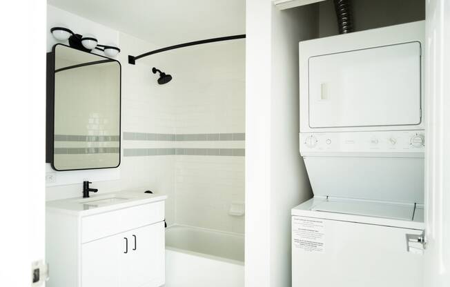 a white washer and dryer and a mirror in a bathroom