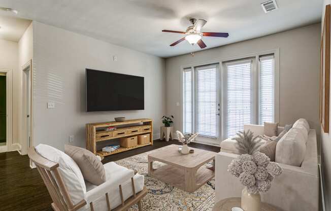 a living room with a ceiling fan and a tv