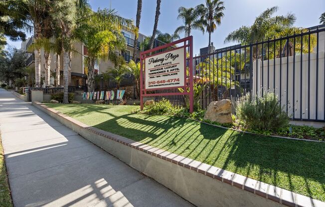 a sign on a lawn in front of a building with palm trees