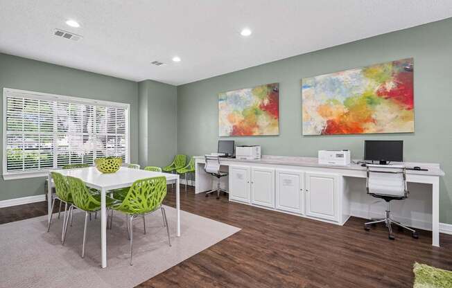 Business center room in the leasing office with a white desk and green chairs.