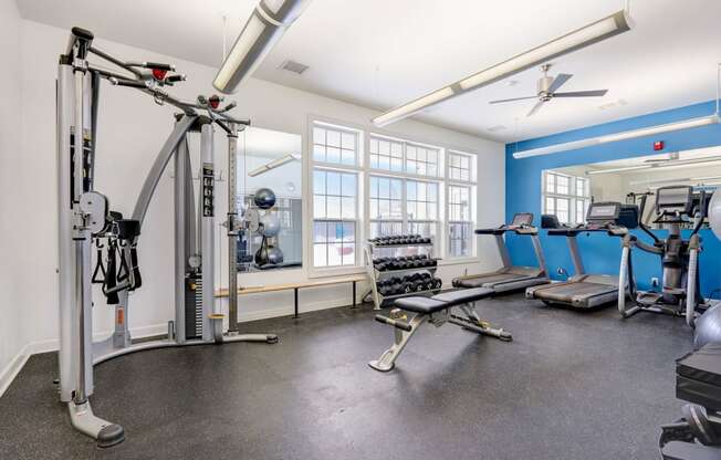 a gym with weights and cardio equipment and windows