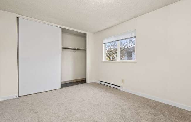 an empty room with white walls and a window and a closet