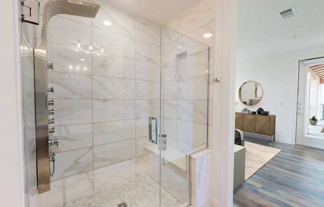 the master bathroom has a large shower with marble tiles and a wood floor