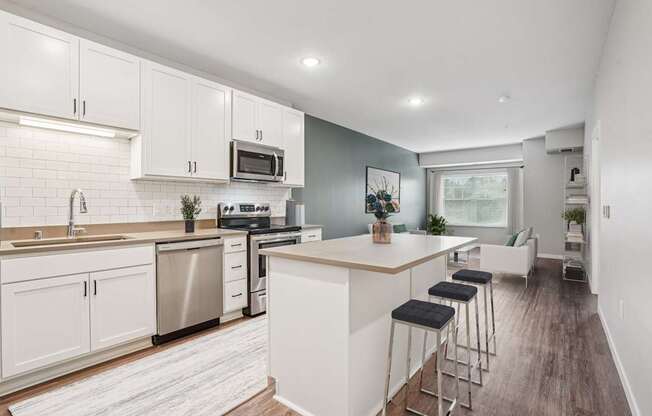 A kitchen with white cabinets and a wooden island.