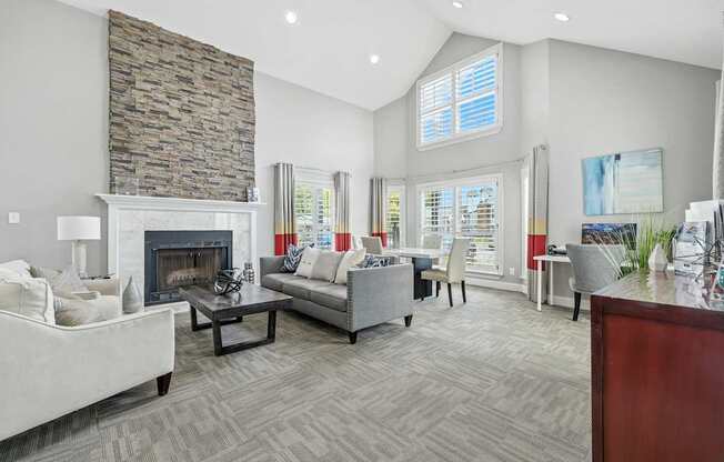 A living room with a stone fireplace and grey couches.