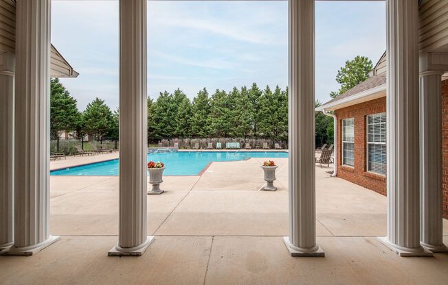 a view of a swimming pool from a patio with columns