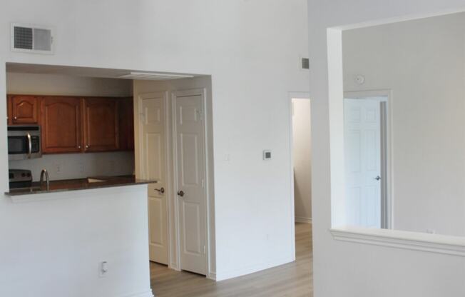 an empty living room and kitchen with a ceiling fan