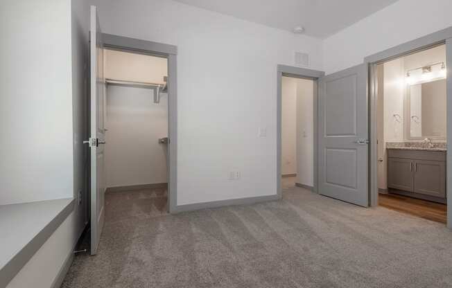 a bedroom with two closets and a bathroom with a sink and a mirror