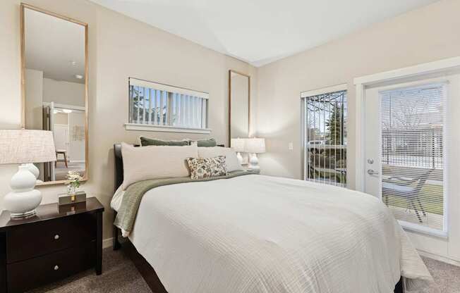 A bedroom with a large bed, a dresser with a mirror, and a window with blinds.