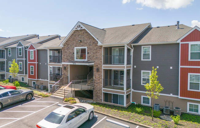 a row of apartment buildings with cars parked in a parking lot