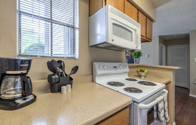 A kitchen with a white stove top oven and a white microwave above it.