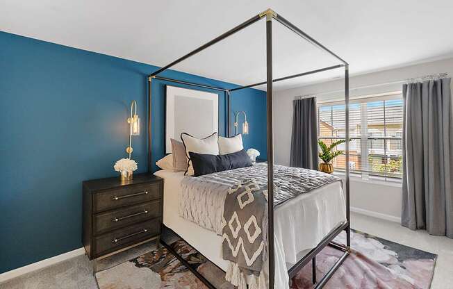 A bedroom with a four poster bed and a dresser.