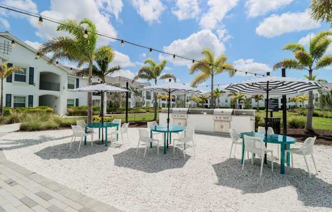 Community grilling stations with umbrella covered table with chairs located in Naples,FL