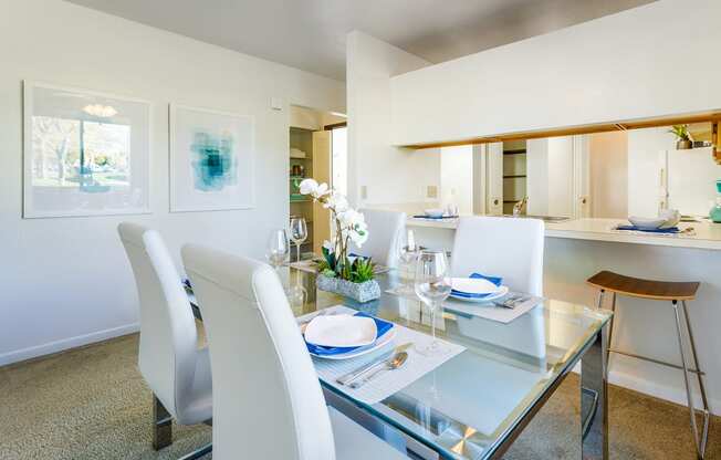 a dining area with a glass table and white chairs