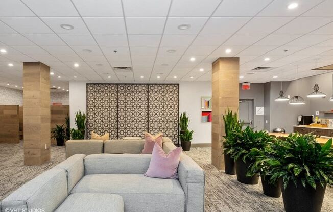 a large room with a large couch and potted plants