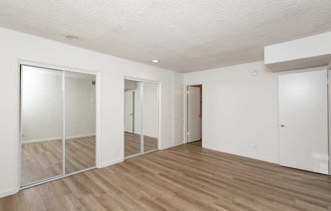 Bedroom with Mirrored Wardrobe Closet and Hardwood Floors