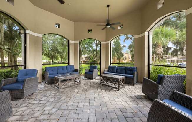 a covered patio with chairs and tables and large windows