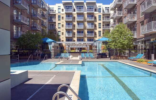 an apartment swimming pool with an apartment building in the background