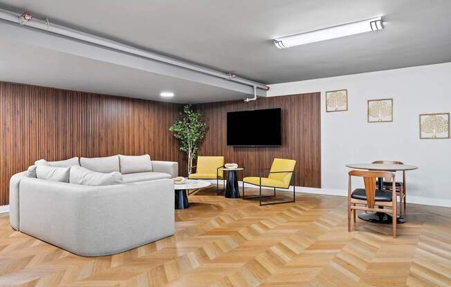 A living room with a grey sofa, a yellow chair, a small table, and a television.
