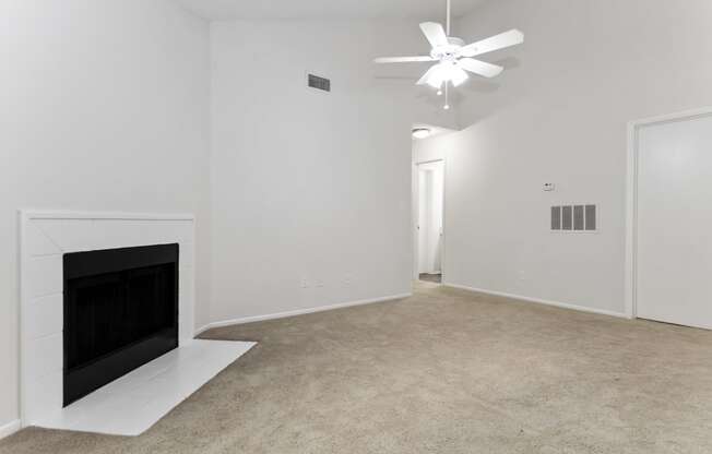 a living room with a fireplace and a vaulted ceiling and fan at Canopy at Baybrook apartments in Charlotte NC