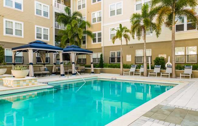 a swimming pool with palm trees in front of a building