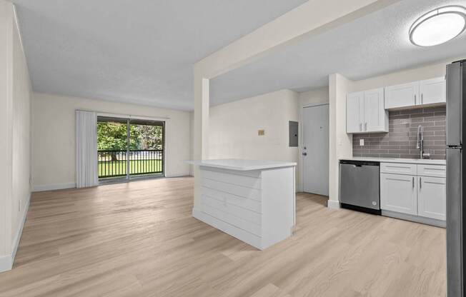 A kitchen with white cabinets and a wooden floor.