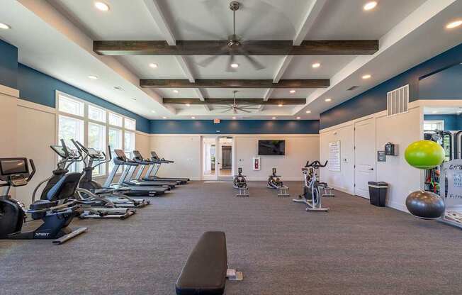 A gym with a variety of exercise equipment including treadmills, stationary bikes, and weights.