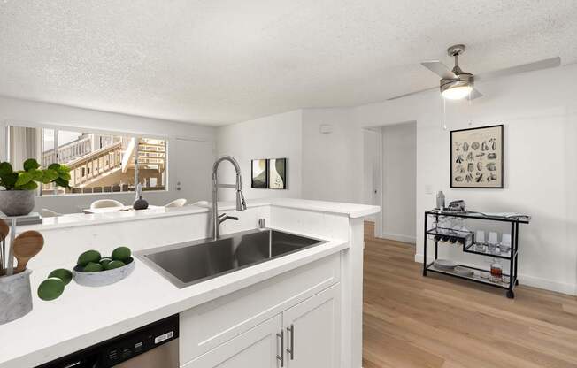 A kitchen with white cabinets and a stainless steel sink.
