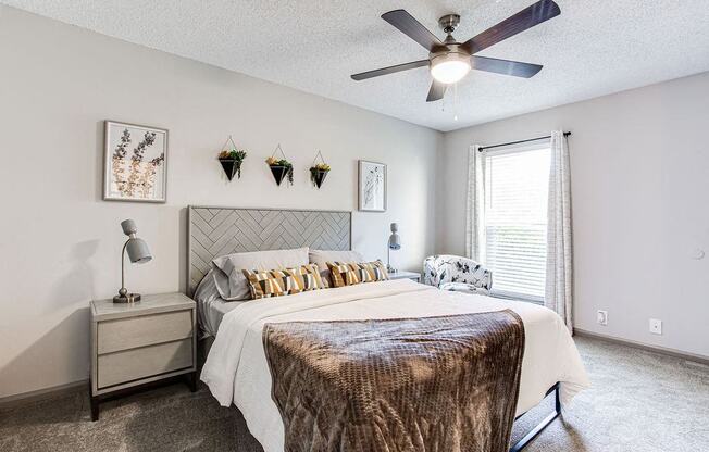 A bedroom with a bed, nightstand, and ceiling fan.