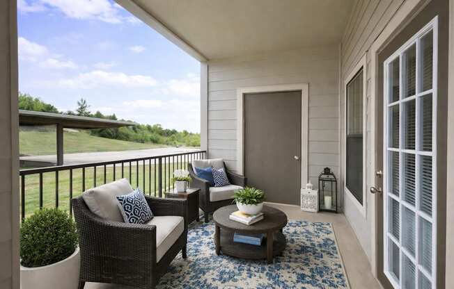 A balcony with a sofa, chair, and table with a plant on it.