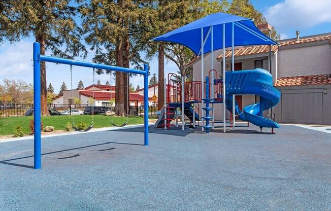 Community Playground with a Slide, Swing Set and Blue Canopy at Creek 2645 Apartments in Sacramento, CA.