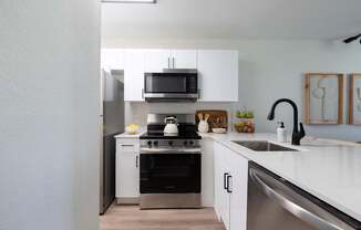 A modern kitchen with white cabinets and stainless steel appliances.