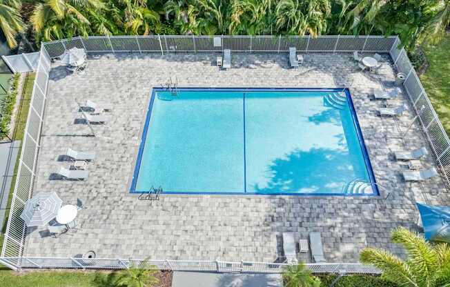 A rectangular pool surrounded by a fence and chairs.