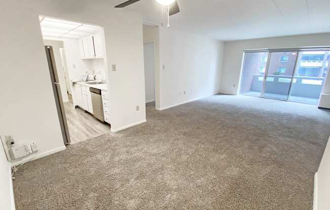 an empty living room with a kitchen in the background