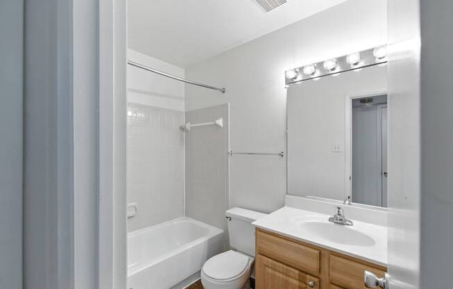 A white bathroom with a toilet, sink, and bathtub.
