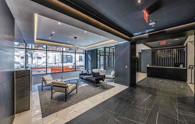 Lobby of 3thirty3 New Rochelle NY high-rise, with fireplace, marble floors, modern furniture, floor-to-ceiling windows with street view, and concierge desk.